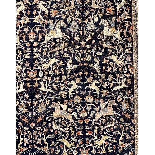 121 - A large Persian rug decorated with figures on horseback, on a blue ground, 312 by 442cms.