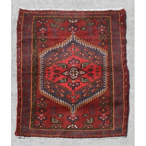 129 - A Persian Hamadan hand knotted woollen rug with stylised design within borders, on a red ground, 140... 