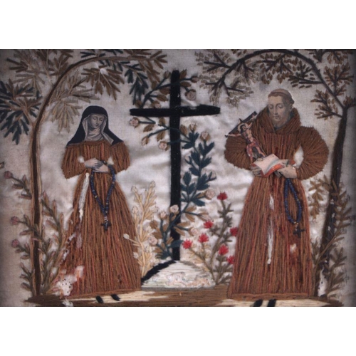 248 - An 18th /19th century wool work picture depicting a nun and a monk standing beside a crucifix with e... 