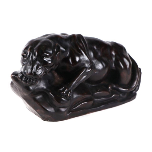 556 - A bronzed resin figure of a crouching lioness on a rocky base, signed 'J. Lee', 46cm wide.