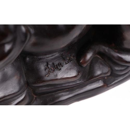 556 - A bronzed resin figure of a crouching lioness on a rocky base, signed 'J. Lee', 46cm wide.