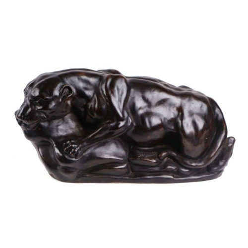 556 - A bronzed resin figure of a crouching lioness on a rocky base, signed 'J. Lee', 46cm wide.