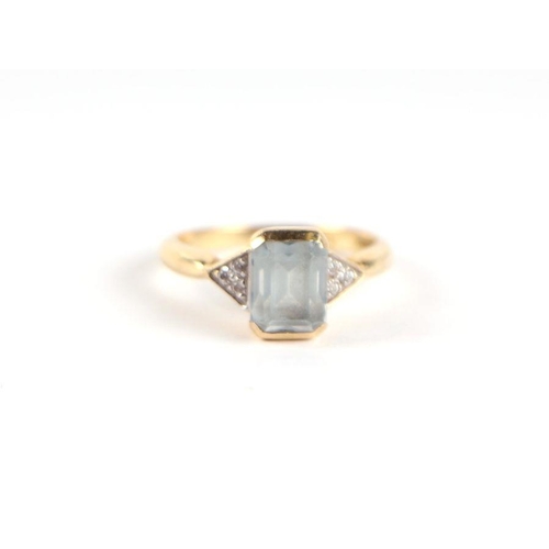 718 - An 18ct gold aquamarine and diamond ring, the central emerald cut aquamarine flanked by diamond set ... 