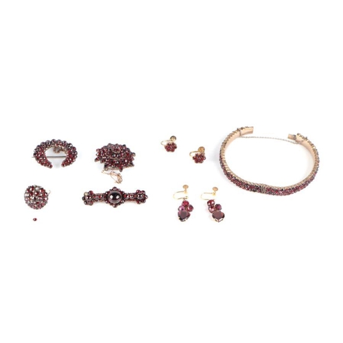 738 - A selection of garnet set jewellery to include a bangle; a flowerhead cluster brooch; a half moon br... 