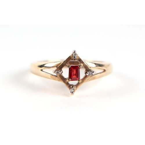 747 - A 9ct gold red stone and diamond ring, the central emerald cut red stone flanked by four small diamo... 