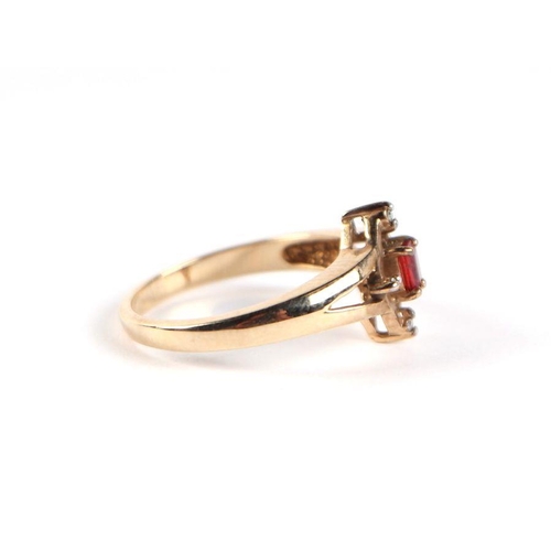 747 - A 9ct gold red stone and diamond ring, the central emerald cut red stone flanked by four small diamo... 