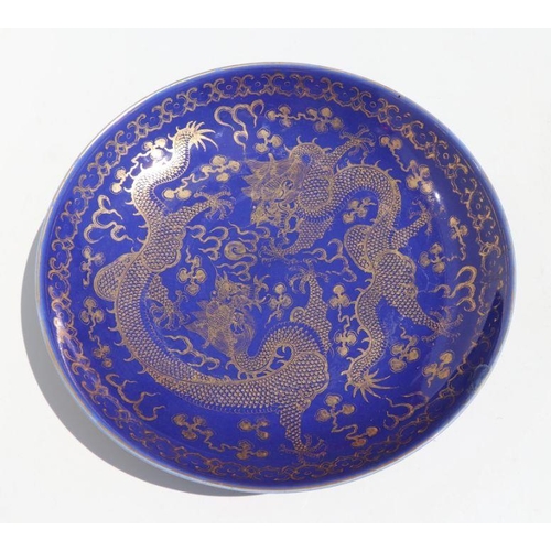 786 - A Chinese gilt decorated blue ground bowl depicting dragons amongst clouds chasing a flaming pearl, ... 