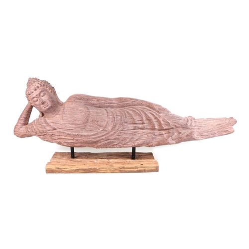 825 - A large moulded composite stone effect reclining Buddha mounted on a driftwood stand, 169cms long.