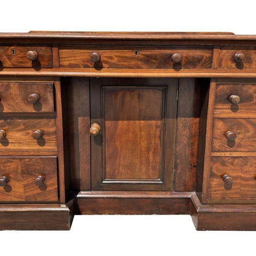 925 - A Victorian mahogany kneehole desk with an arrangement of nine drawers and central cupboard, on a pl... 