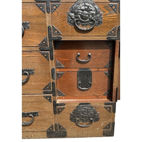 932 - A Korean chest with an arrangement of six drawers and a cupboard with fitted interior, with iron han... 