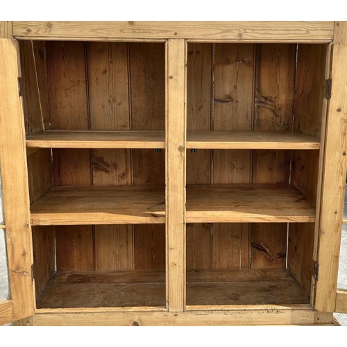 949 - A stripped pine dresser, the superstructure with glazed doors and cupboard beneath, 106cm wide.