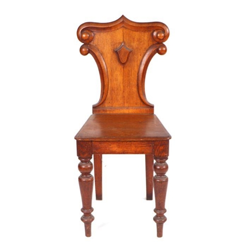 965 - A Victorian oak hall chair with shield shaped back, solid seat and turned front legs.