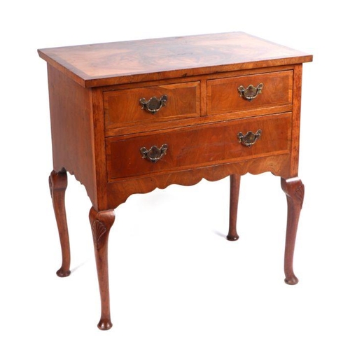 993 - A Queen Anne style figured walnut lowboy, the rectangular figured walnut top above an arrangement of... 