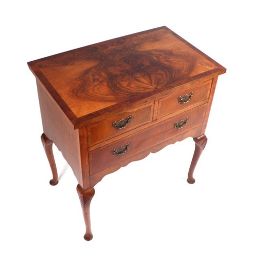 993 - A Queen Anne style figured walnut lowboy, the rectangular figured walnut top above an arrangement of... 