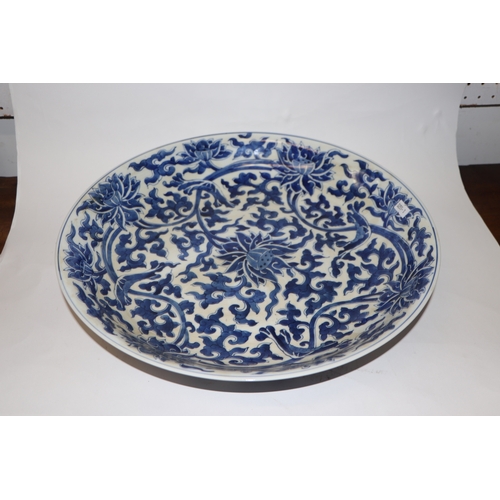 881 - A large Chinese blue and white shallow bowl decorated with flowering foliage, six character mark to ... 