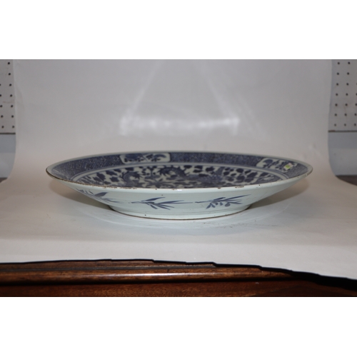 881 - A large Chinese blue and white shallow bowl decorated with flowering foliage, six character mark to ... 