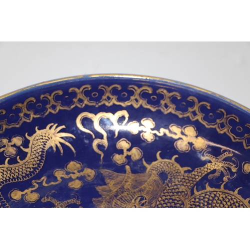 786 - A Chinese gilt decorated blue ground bowl depicting dragons amongst clouds chasing a flaming pearl, ... 