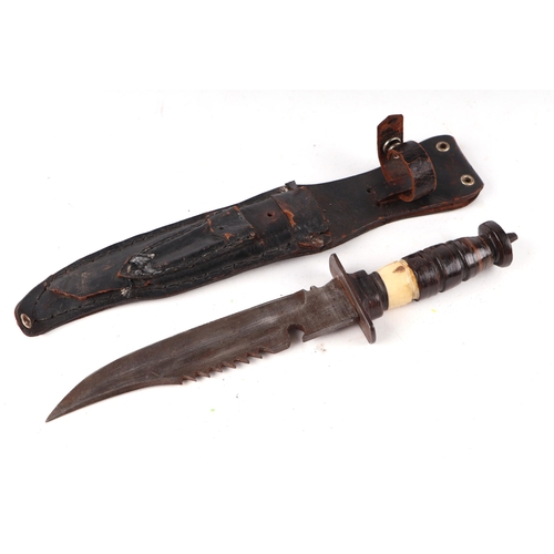 115 - An early 20th century sawback Bowie knife in its leather scabbard. Havinga part bone hilt. Blade len... 