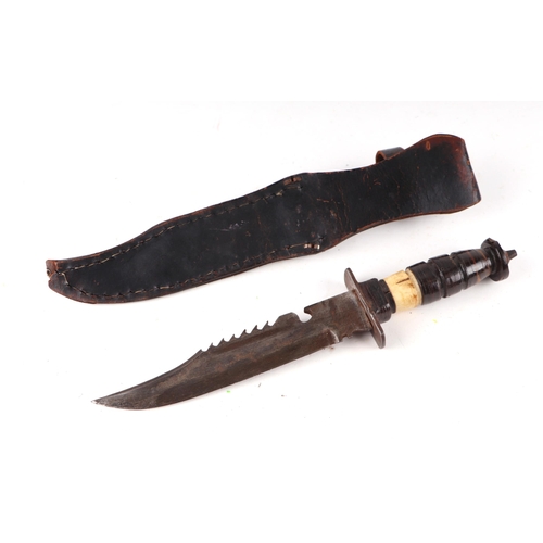 115 - An early 20th century sawback Bowie knife in its leather scabbard. Havinga part bone hilt. Blade len... 