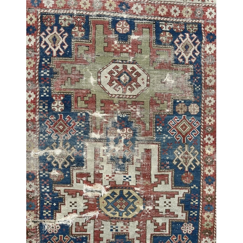 142 - An antique Caucasian rug, 100 by 114cms (wear and damages).