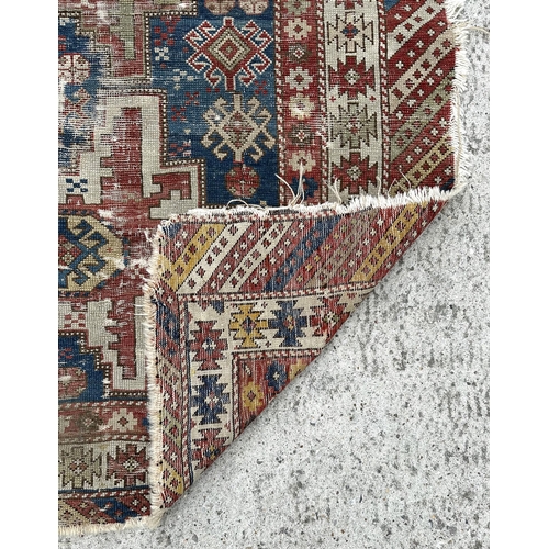 142 - An antique Caucasian rug, 100 by 114cms (wear and damages).