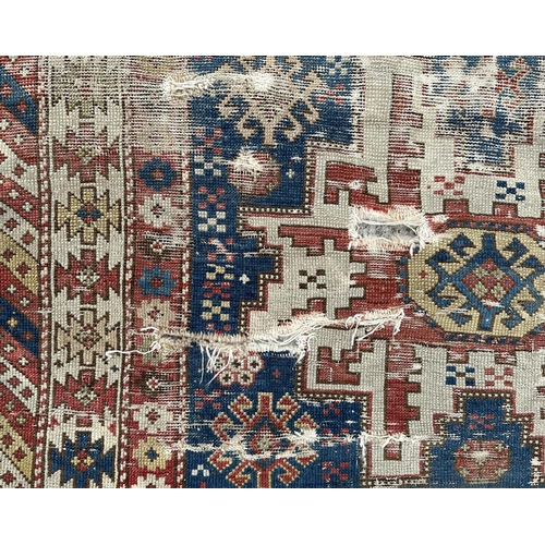 142 - An antique Caucasian rug, 100 by 114cms (wear and damages).