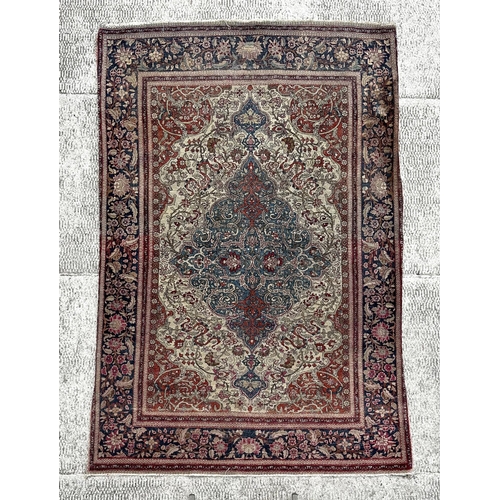 147 - A Persian Nain silk and wool rug with central blue medallion on a red ground within a multi floral b... 