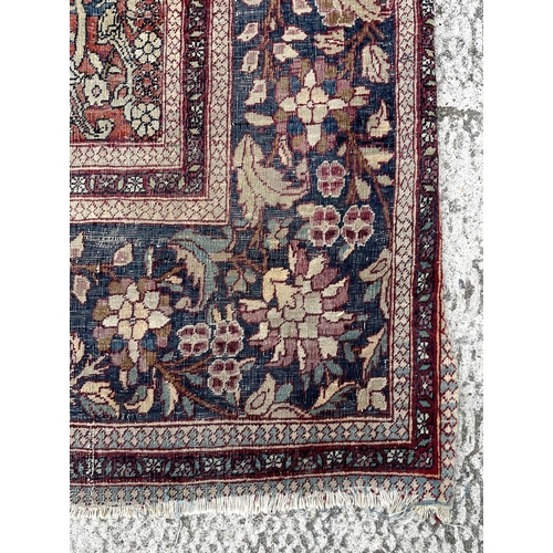 147 - A Persian Nain silk and wool rug with central blue medallion on a red ground within a multi floral b... 