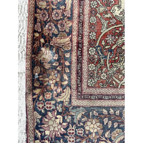 147 - A Persian Nain silk and wool rug with central blue medallion on a red ground within a multi floral b... 