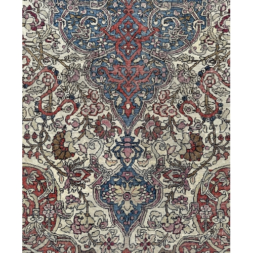 147 - A Persian Nain silk and wool rug with central blue medallion on a red ground within a multi floral b... 