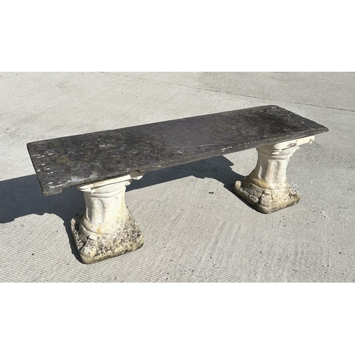 15 - A garden bench with reconstituted stone pedestals and a slate seat, 128cm wide.