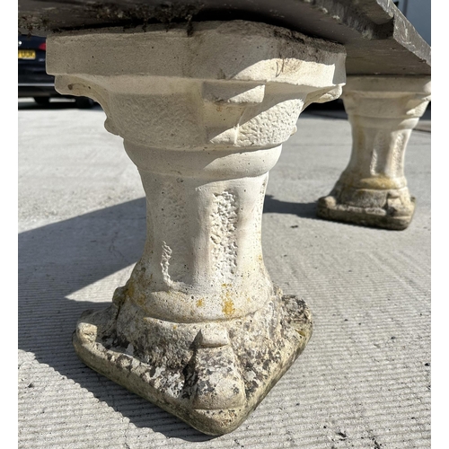 15 - A garden bench with reconstituted stone pedestals and a slate seat, 128cm wide.