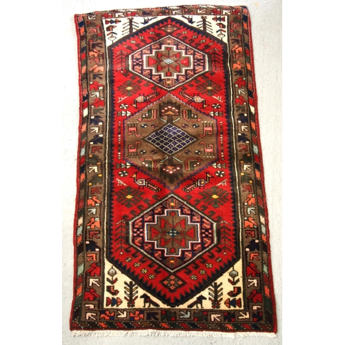 152 - A Persian Hamadan hand knotted woollen rug with stylised design within borders, on a red ground, 163... 