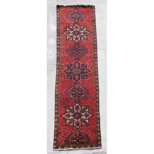 154 - A Persian hand knotted runner with repeat star design within floral borders, on a red ground, 380 by... 