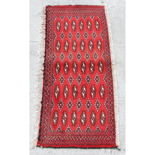 159 - A Persian Turkoman woollen hand-made small rug with geometric designs on a red ground, 130 by 48cms.