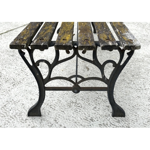 17 - A well weathered slatted wooden garden bench with cast iron supports, 122cm wide.