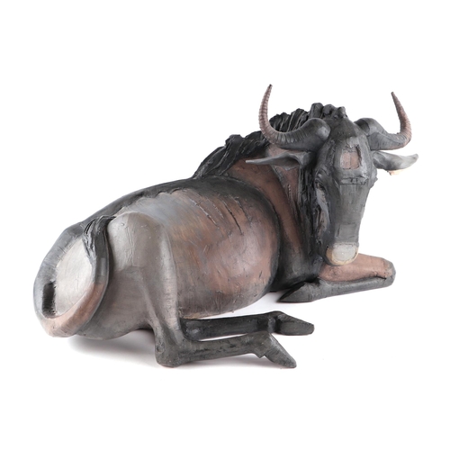 378 - Nichola Theakston MA (modern British) - a ceramic reclining wildebeest sculpture, 75cm wide.