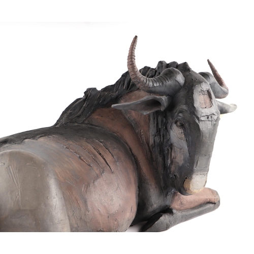 378 - Nichola Theakston MA (modern British) - a ceramic reclining wildebeest sculpture, 75cm wide.