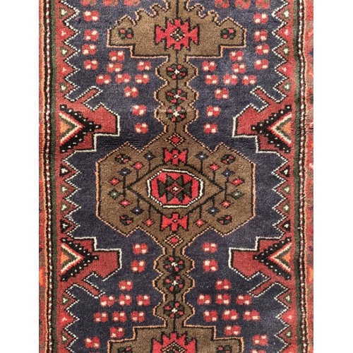 120 - A Persian Hamadan wool carpet with geometric design and stylised birds within borders, on a red grou... 