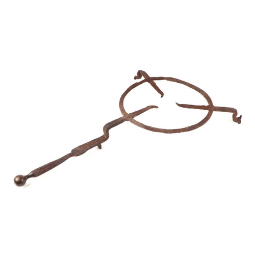 402 - A large 17th / 18th century wrought iron hearth trivet with brass ball handle, 68cms overall length.