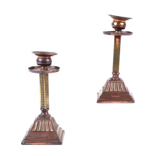 409 - A pair of Arts & Crafts style copper and brass candlesticks with stepped square bases, 17cms high.