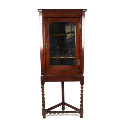 893 - A 19th century oak corner cupboard on stand, the single glazed door enclosing a shelved interior, on... 