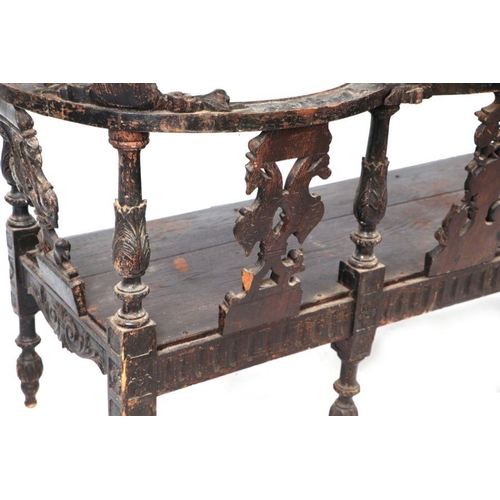 899 - An early 19th century continental oak window seat with cherub head and griffin carvings and dragon h... 