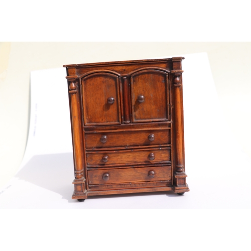 422 - A 19th century apprentice piece, a miniature cabinet, the pair of cupboard doors above three long dr... 