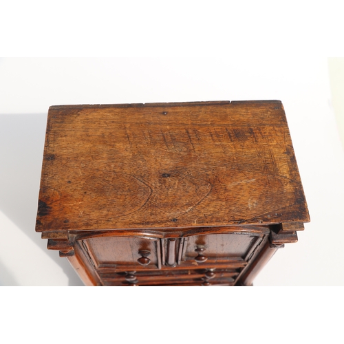 422 - A 19th century apprentice piece, a miniature cabinet, the pair of cupboard doors above three long dr... 