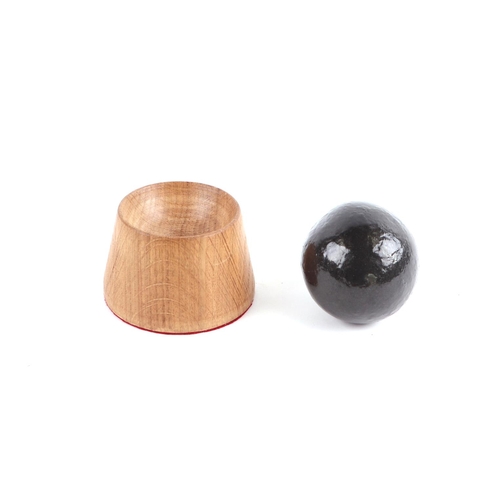 115 - A roundshot cannon ball. Approximate diameter of 6.5cms (2.5ins) mounted on a turned oak mount