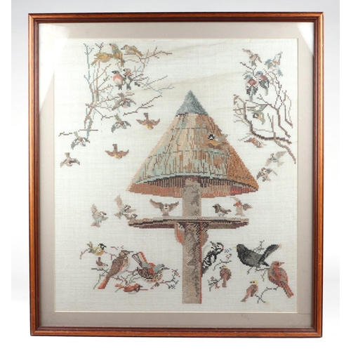 126 - A 20th century cross stitch embroidered panel depicting woodland birds on a bird feeder, framed & gl... 