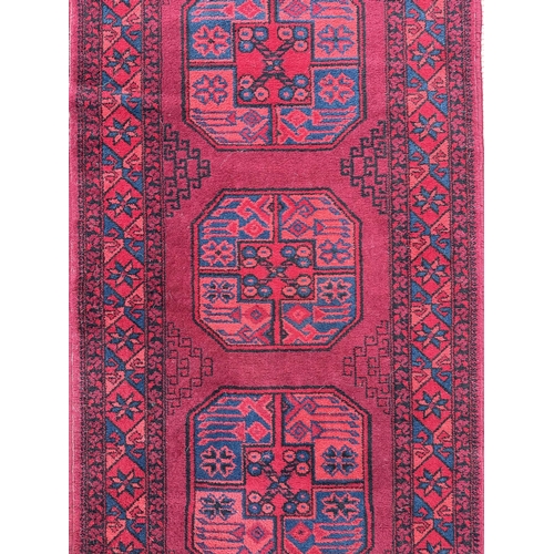 129 - A Persian rug with central guls within a multi border, on a red ground, 140 by 70cms.