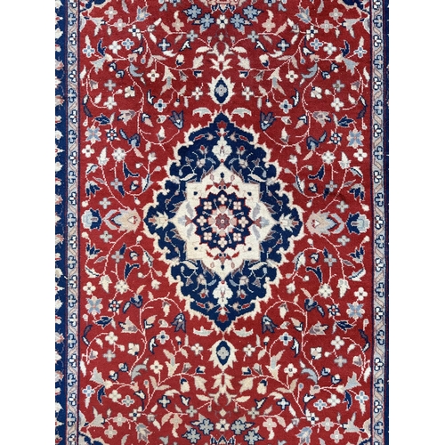 133 - A modern Persian rug decorated with foliate scrolls, on a red ground; together with another similar ... 