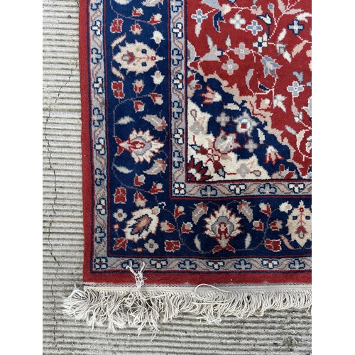 133 - A modern Persian rug decorated with foliate scrolls, on a red ground; together with another similar ... 